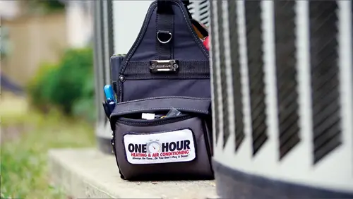 A One Hour AC Tech's bag sitting on concrete next to an outside unit